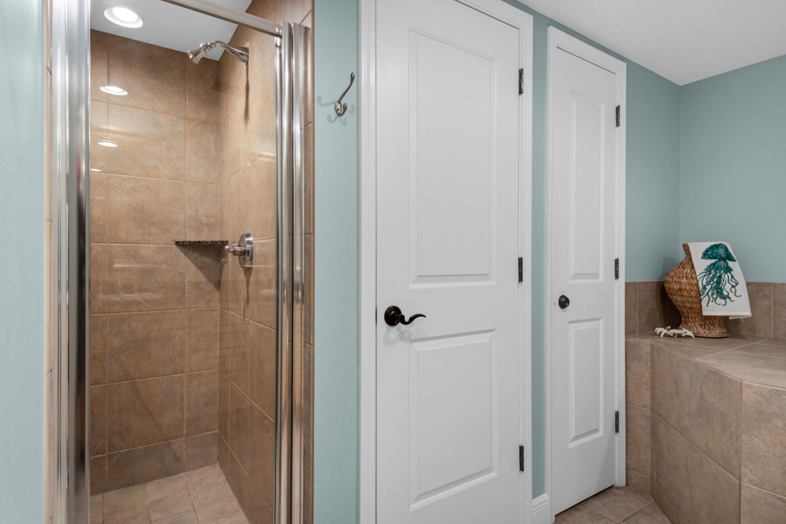 Een badkamer met een douchecabine van glas, witte deuren en een handdoekhouder.