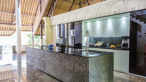 Una cocina moderna con una isla central, electrodomésticos integrados y un techo alto con estructura de madera.