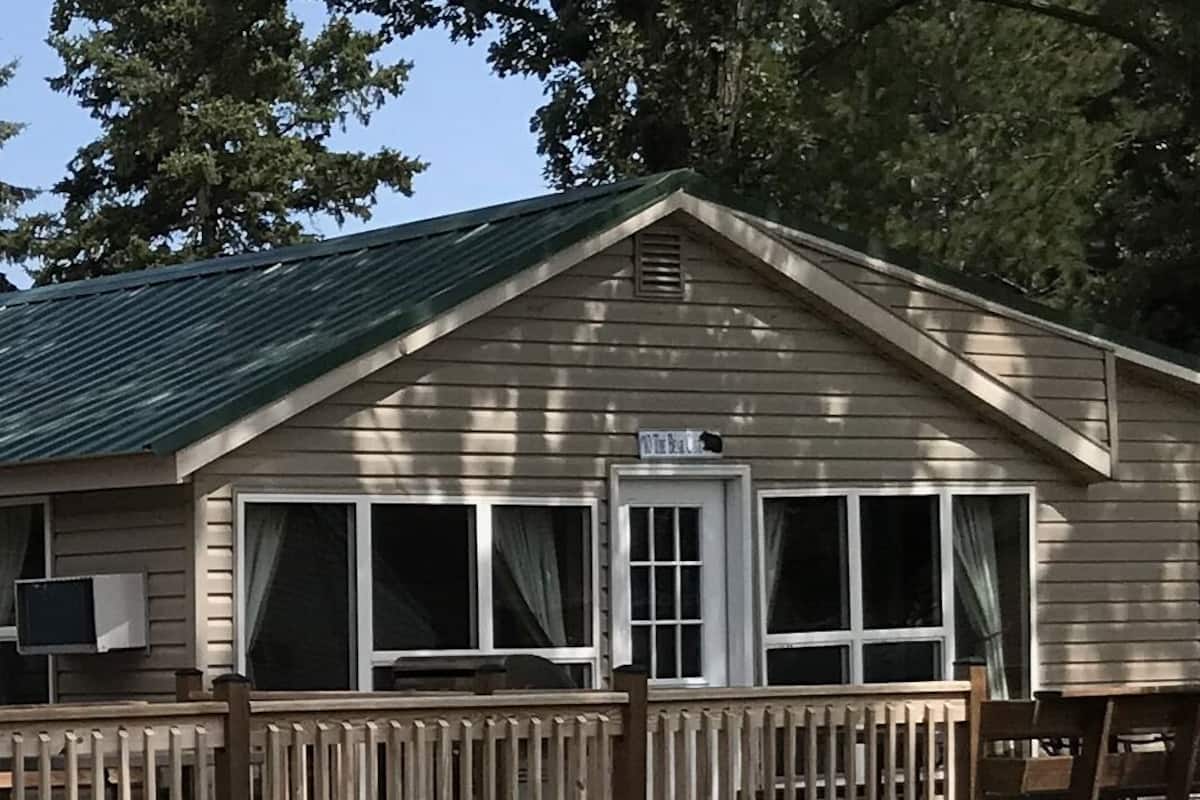 A wooden cabin with a porch, a door, and a window.