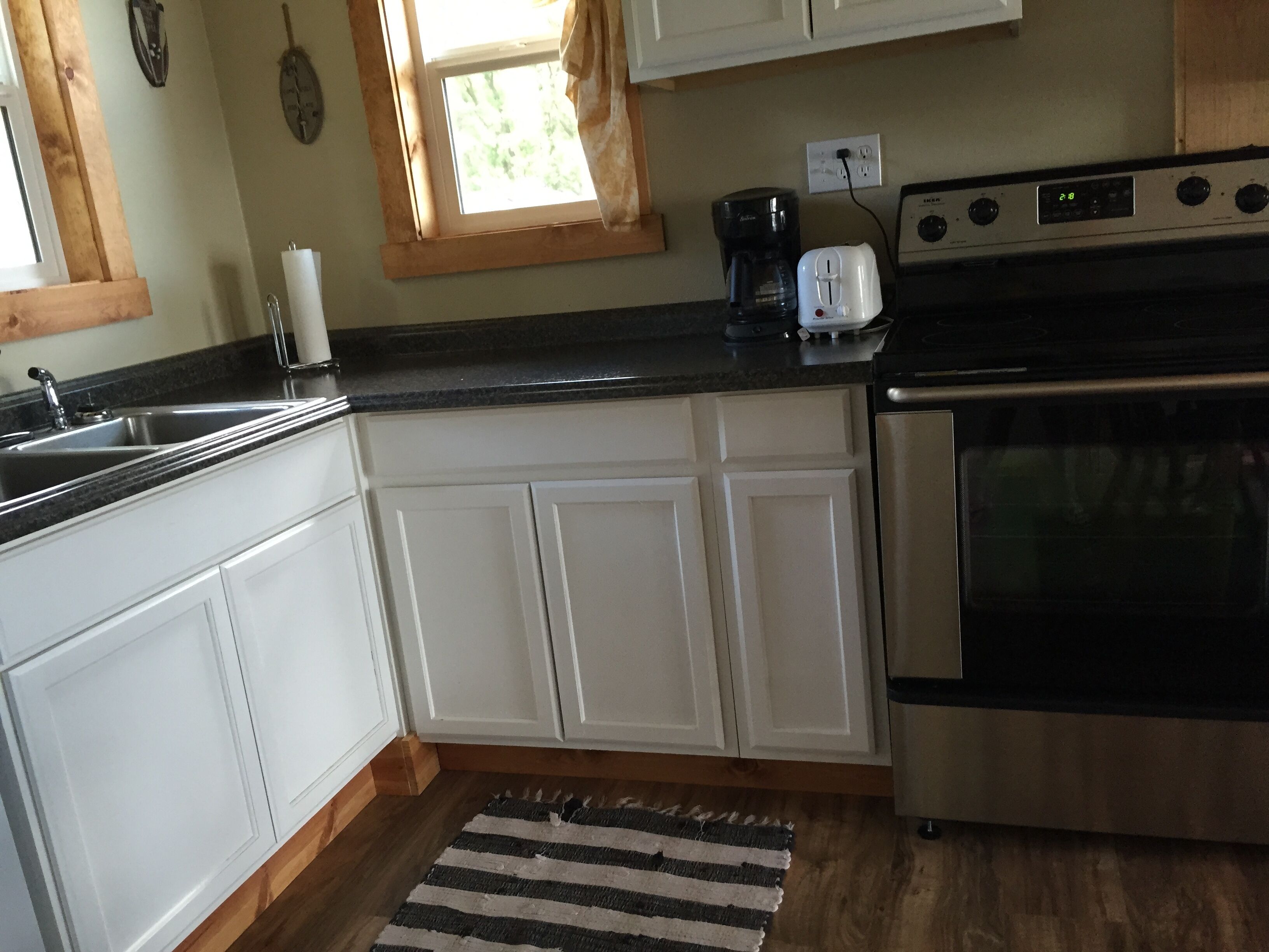 A kitchen with white cabinets, a stainless steel stove, a coffee maker, and a toaster.