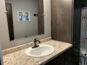 A bathroom with a white sink, dark cabinetry, and a mirror with a blue and white design. - Hollys Resort (Battle Lake)