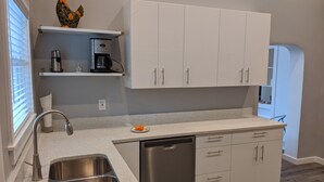A modern kitchen with a stainless steel sink, white cabinetry, a coffee maker, and a dish drying rack. - Stylish, Salt Lake City, Home (Salt Lake City)