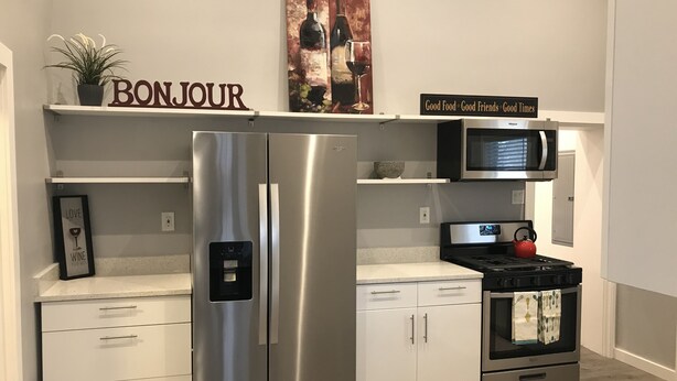 A modern kitchen with a stainless steel refrigerator, a microwave, an oven, and a water dispenser. There are white cabinets and a countertop. - Stylish, Salt Lake City, Home (Salt Lake City)