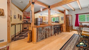 A spacious kitchen with wooden beams, a central island with stools, and a view of the outdoors through a window. - Fishing pond, 15 minutes to Nashville (Nashville)