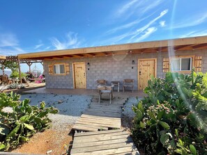 A rustic building with a wooden deck, a covered patio area, and a gravel path leading to the entrance. - Sn Tony Hotel & Spa (Valle de Guadalupe)