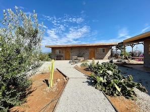 A rustic house with a stone facade, a wooden porch, and a gravel pathway leading to the entrance. - Sn Tony Hotel & Spa (Valle de Guadalupe)