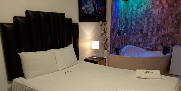 A hotel room with a bed, a nightstand with a lamp, a wall-mounted artwork, and a bathtub. - Hotel Septima Maravilla Lunahuana (Lunahuana)