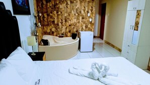 Een hotelkamer met een bed, een badkamer met een bad, een koelkast en een kledingkast.