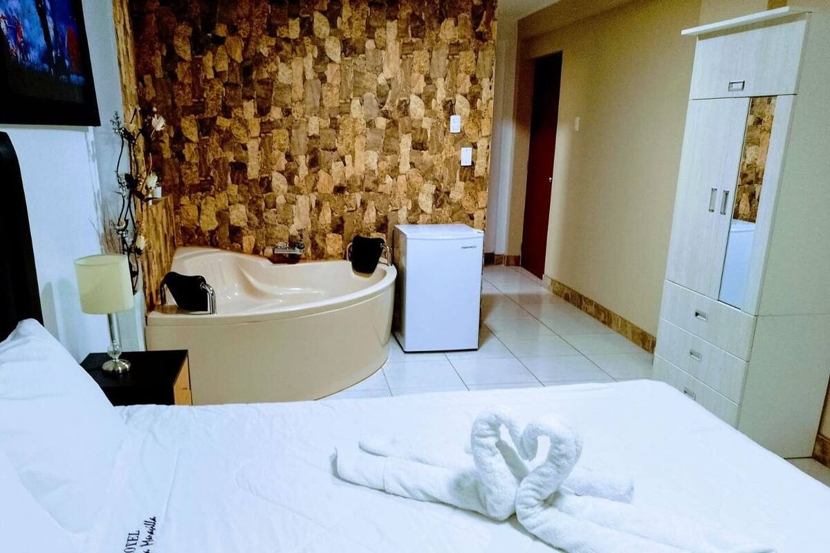 Ein Hotelzimmer mit Bett, Badezimmer mit Badewanne, Kühlschrank und Kleiderschrank.