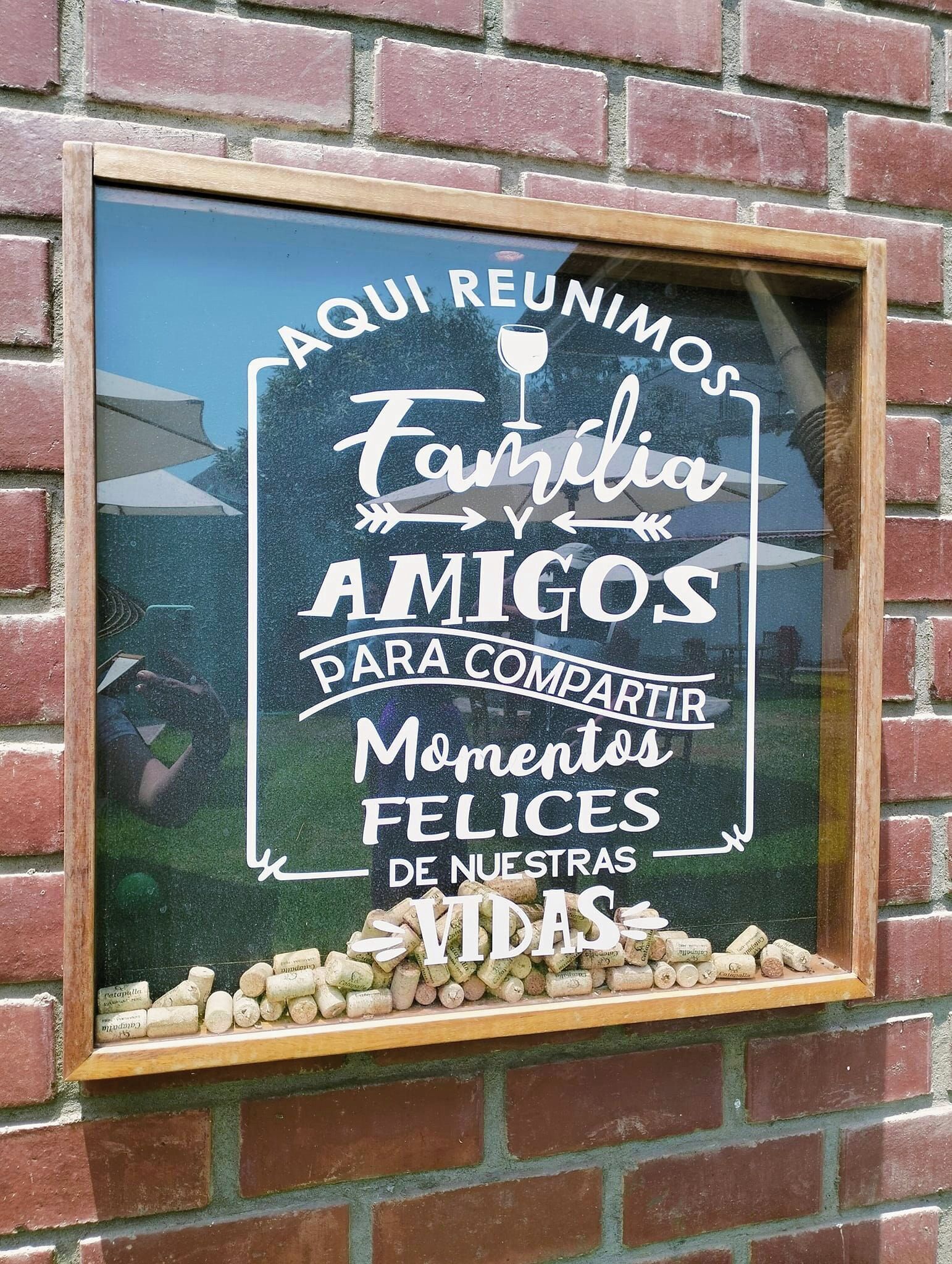 A framed sign with text in Spanish, placed on a brick wall.