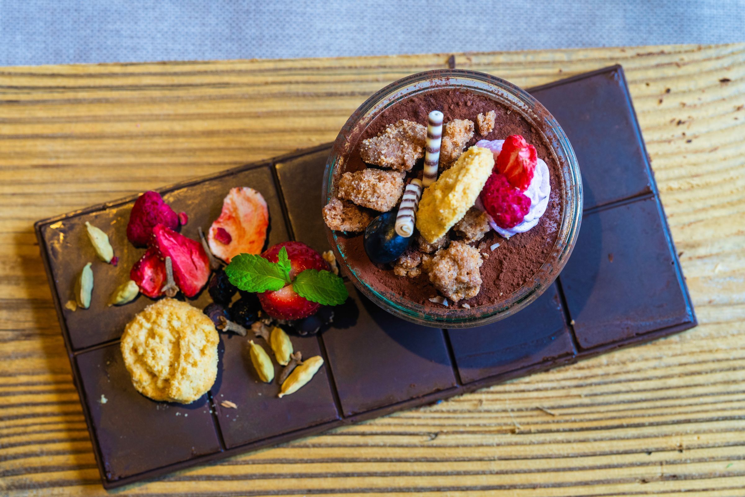 Dessert med chokolademousse, jordbær, hindbær og nødder på en chokoladeplade.
