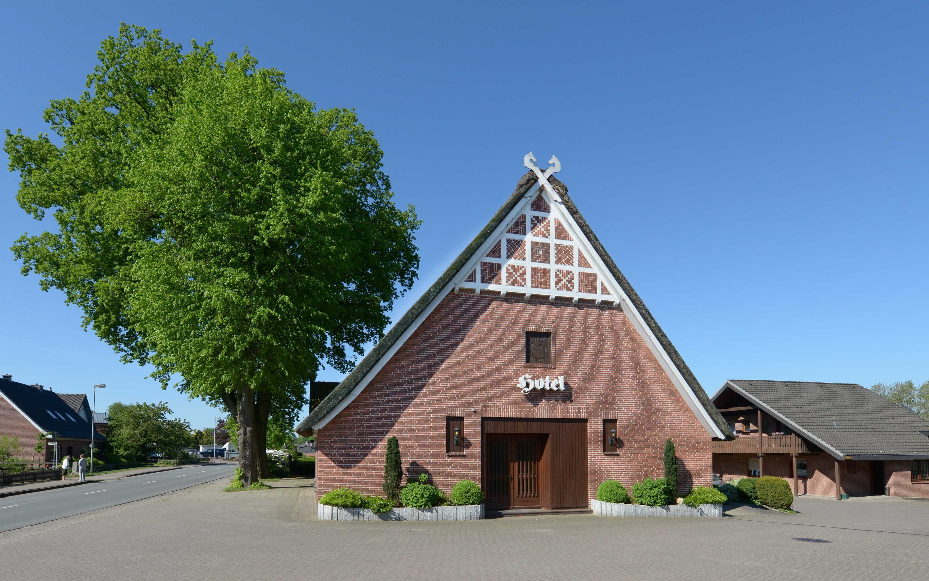 A brick building with a triangular roof and a sign that reads "Hotel".
