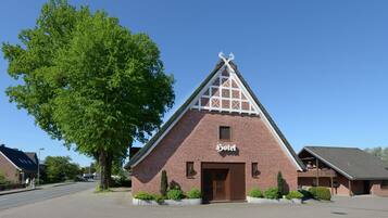 A brick building with a triangular roof and a sign that reads "Hotel".