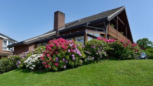 A modern house with a sloped roof, large windows, and a brick chimney. - Standard Double Room - Landhotel Zur Eiche (Buxtehude)