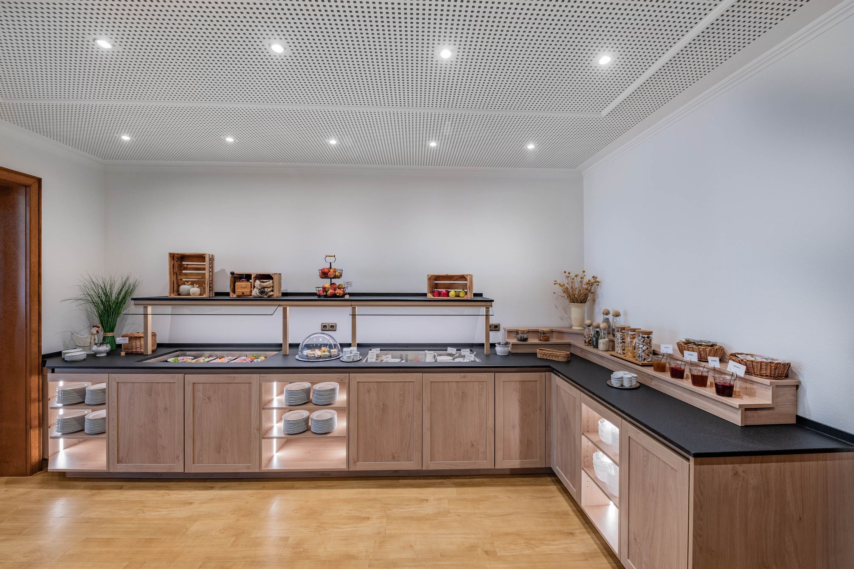 Una cucina moderna con mobili in legno, un piano di lavoro nero e diversi prodotti alimentari esposti.