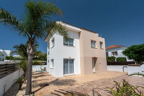 Une maison moderne à deux étages, avec une façade blanche et un toit recouvert de tuiles rouges.