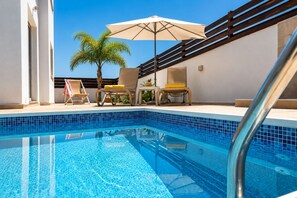 A swimming pool with clear blue tiles, surrounded by lounge chairs and a palm tree. - Narcissos Villa 2 - Three Bedroom Villa, Sleeps 8 (Protaras)