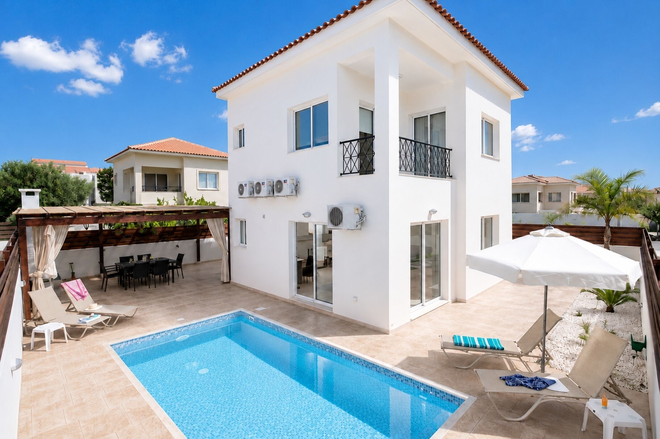 A two-story building with a swimming pool, outdoor seating, and a covered patio area.