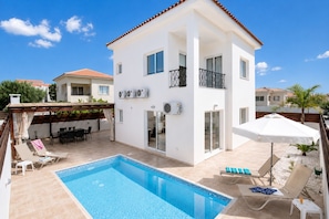 A two-story building with a swimming pool, outdoor seating, and a covered patio area.
