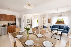A modern apartment with a dining area, kitchen, living room, and a balcony with a view. - Narcissos Villa 2 - Three Bedroom Villa, Sleeps 8 (Protaras)