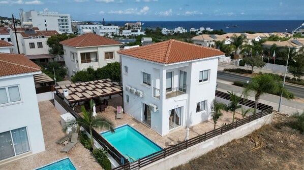 Un quartier résidentiel doté d’une piscine, de bâtiments blancs et offrant une vue sur la mer.