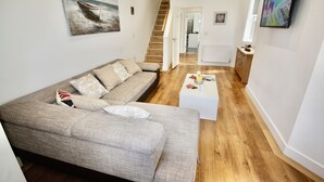 A living room with a sofa, coffee table, and artwork on the walls. - Holiday home hot tub and sauna (Bournemouth)