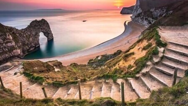 A coastal landscape with a natural arch formation, a beach, and a series of steps leading down to the water. - Holiday home hot tub and sauna (Bournemouth)