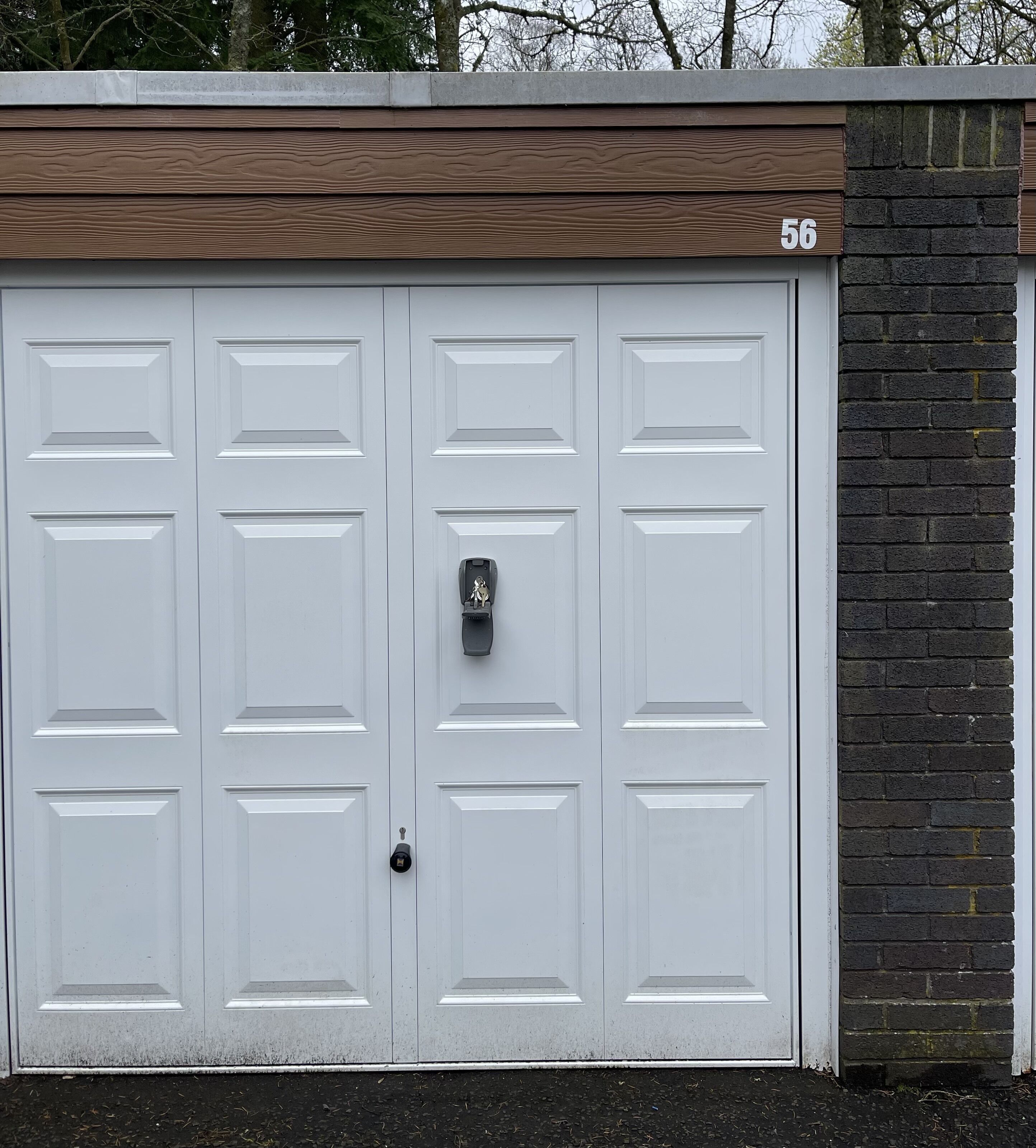 A double garage door with a numeric address sign, a keypad lock, and a small mailbox.
