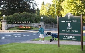 Señal del campo de golf PGA Centenary Course con un carrito de golf y una persona cerca.