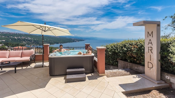 A hot tub with a view of the sea, a sofa, and a sign that reads "MARID."