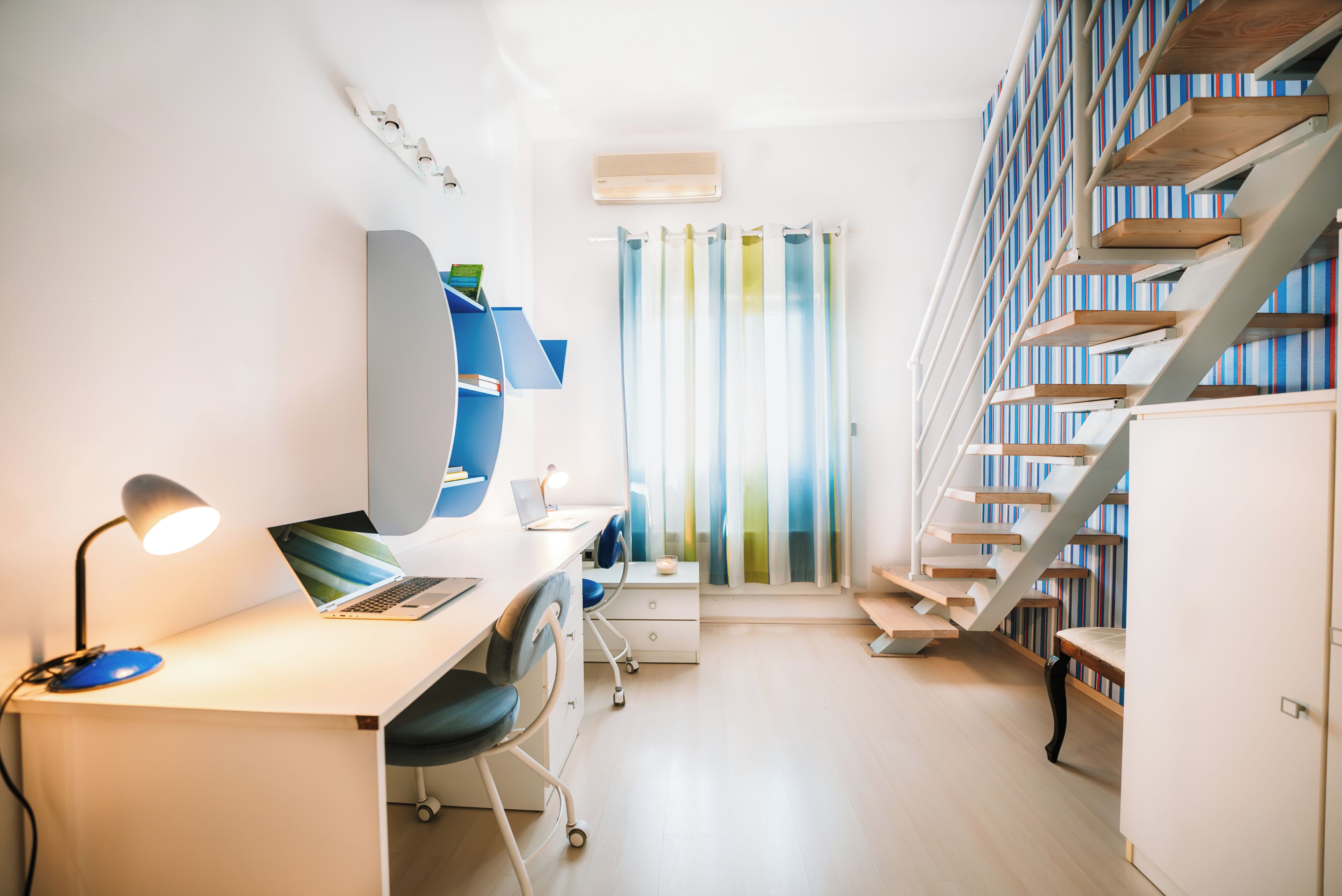 A modern room with a desk, chair, computer, and bookshelves.