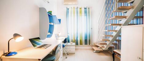 A modern room with a desk, chair, computer, and bookshelves.