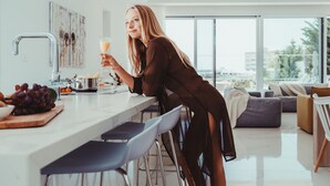 Una cocina moderna con una isla grande, taburetes de bar y vistas a la ciudad a través de amplios ventanales.