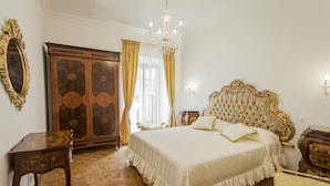 A bedroom with a large bed, a wooden wardrobe, a chandelier, and a mirror. - Holiday home 'Suite Sarandrea' in Rome in the Vatican area of San Pietro (Roma)