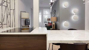 A modern kitchen with a marble countertop, pendant lighting, and a view of the living area. - Moraza Suite by FeelFree Rentals (San Sebastián)