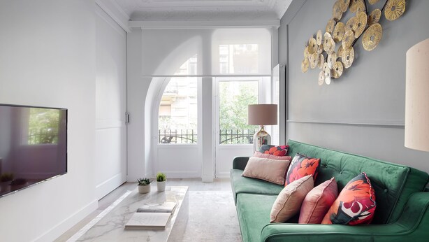A modern living room with a green sofa, a flat-screen TV, and a large window with a view of the city. - Moraza Suite by FeelFree Rentals (San Sebastián)