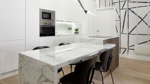 A modern kitchen with a marble countertop, black chairs, and built-in appliances. - Moraza Suite by FeelFree Rentals (San Sebastián)