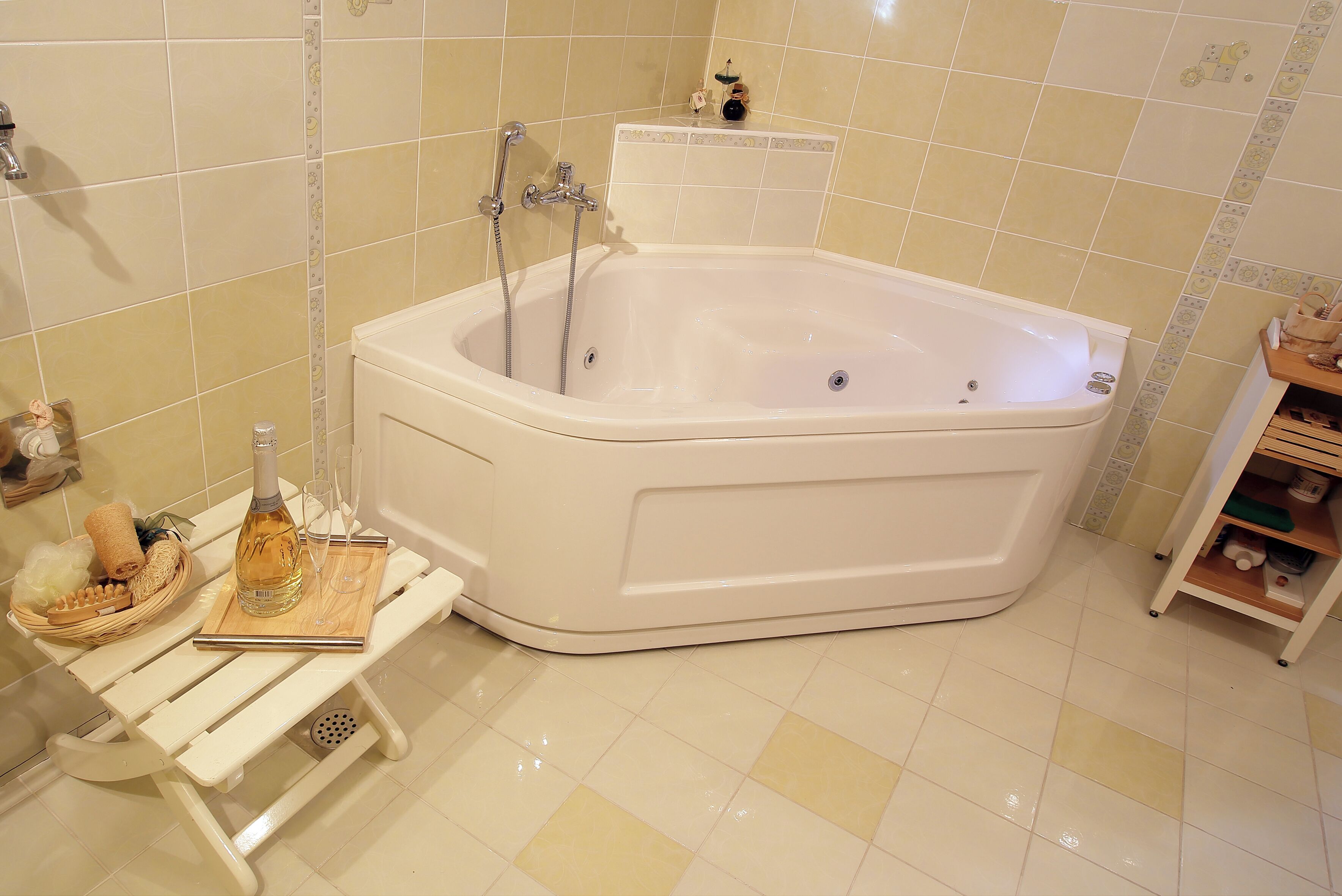 Un baño con bañera, un estante de madera con artículos de aseo y un pequeño estante con objetos decorativos.