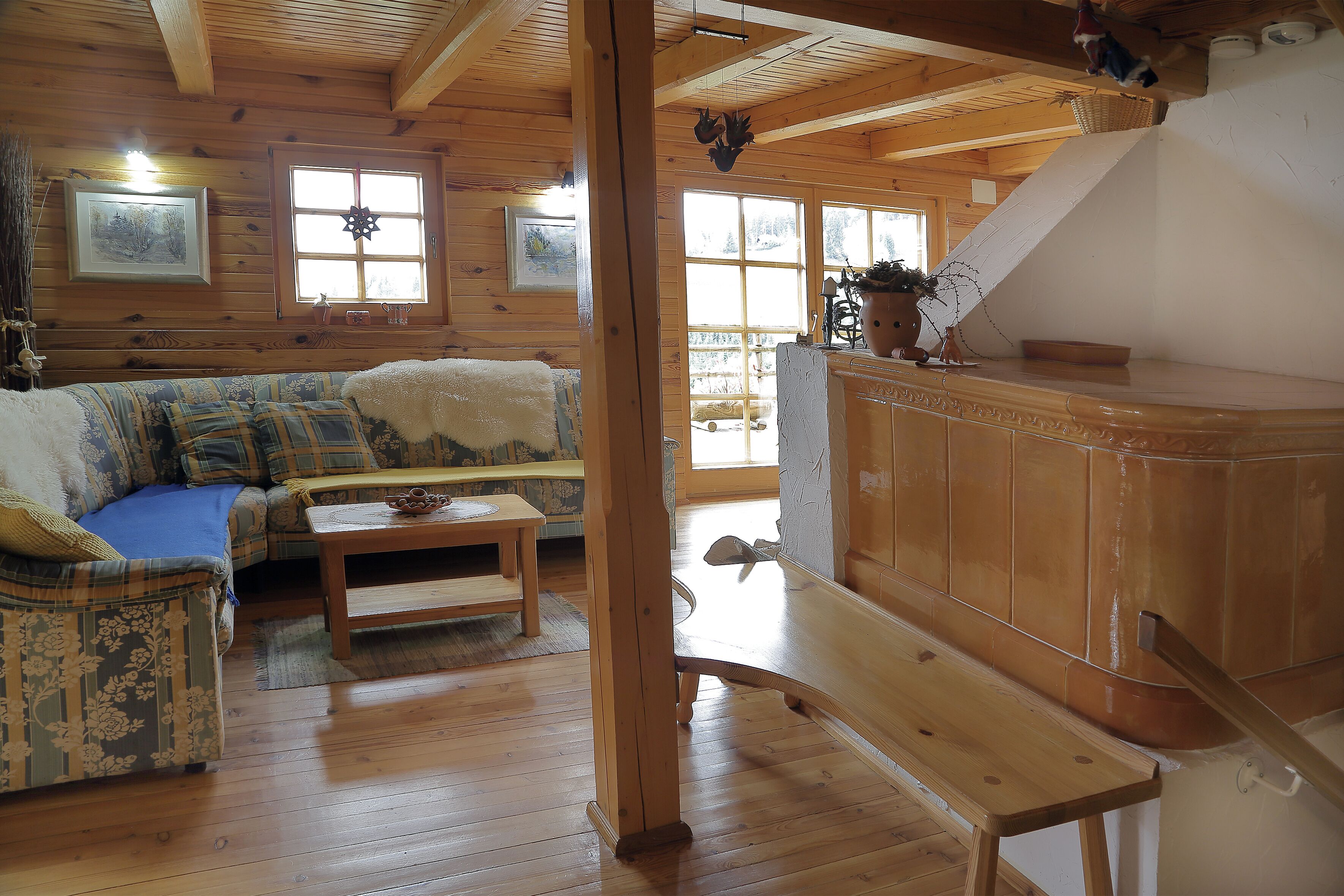 L’intérieur d’une cabane en rondins, avec un plancher en bois, un canapé, une table basse et un escalier.