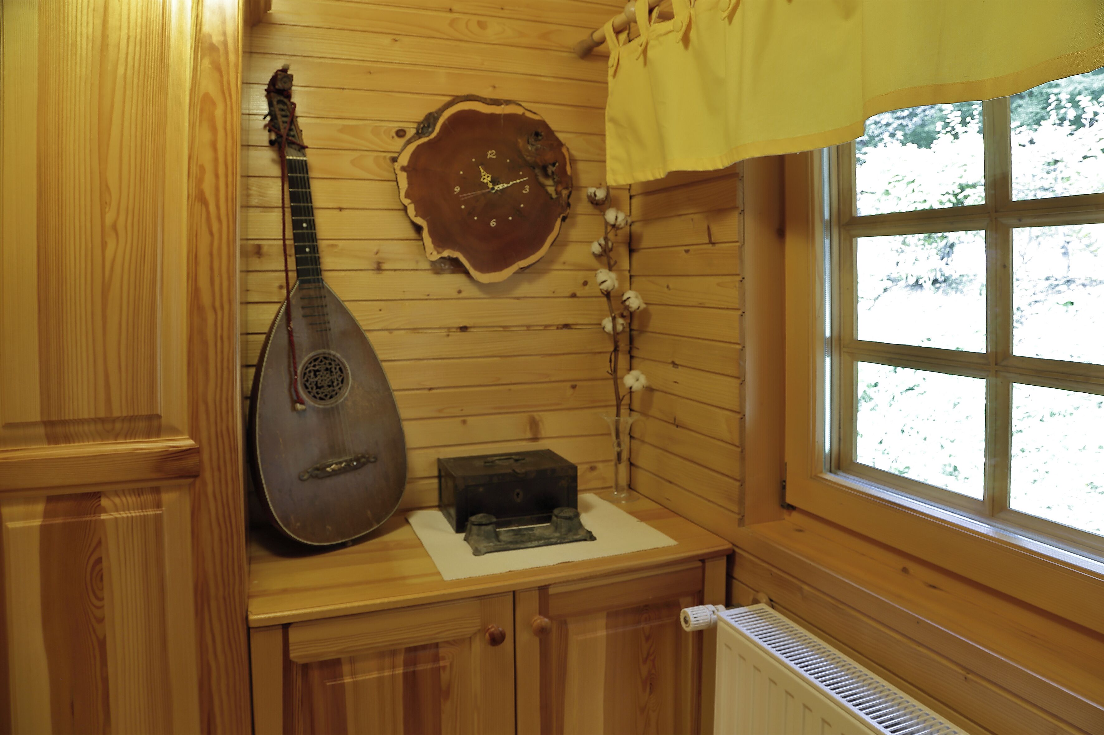 Un intérieur en bois, avec une horloge fixée au mur, une guirlande de boules de coton et une fenêtre donnant sur des arbres.