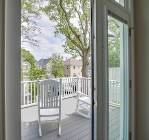 Enjoy the serene view from your deck, featuring a comfortable rocking chair and a railing.
