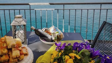 Ein Tisch mit Essen und Blumen auf einem Balkon mit Meerblick.