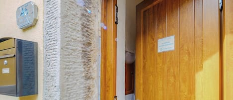 Une porte en bois avec une plaque, une boîte aux lettres et un mur à la texture particulière.