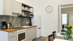 Una cocina moderna con armarios blancos, encimera de madera y microondas integrado.