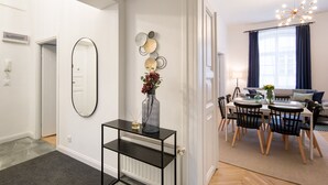 Una sala de estar moderna con comedor, paredes blancas, una consola negra y un espejo grande.