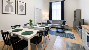 Una sala moderna con sofá, televisión y comedor con sillas y una mesa.