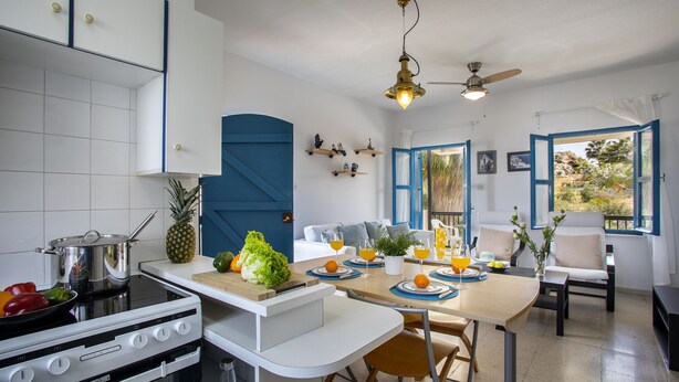 A modern kitchen with a stove, dining table, chairs, and a ceiling fan. - Protaras Ayios Elias Suite (Protaras)