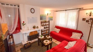 Ein gemütliches Wohnzimmer mit einem roten Sofa, einem Kamin und einem kleinen Tisch mit Dekorationen.