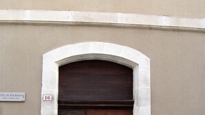 A double wooden door with a white architrave, a sign above it reading "16", and a window with white frames above the door. - 10' from St Rémy and Avignon, charming apartment ***, 2 bedrooms for 4 people (Noves)