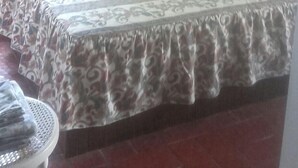 Una camera da letto con soffitto spiovente, un letto con copriletto decorato, una culla bianca e una finestra con tende.